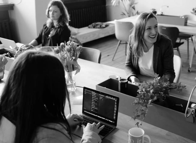 Three women working together at a large co-working desk